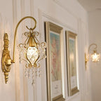 Decorative wall sconce with crystal accents on a wall with framed artwork.