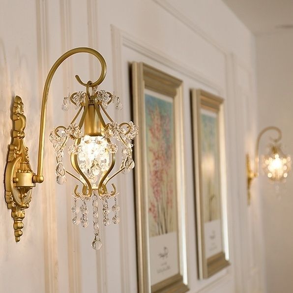 Decorative wall sconce with crystal accents on a wall with framed artwork.