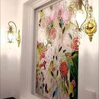 Decorative floral artwork on a wall with ornate wall lights.
