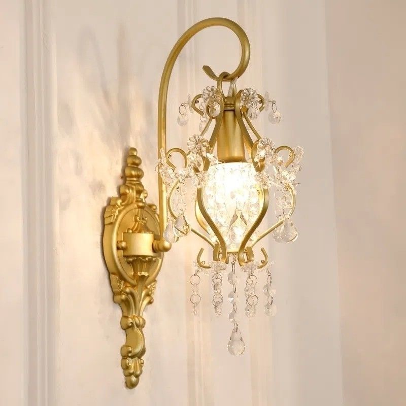 Decorative gold wall sconce with crystal accents on a neutral background