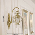 Decorative wall sconce with crystal details on a wall with framed pictures.