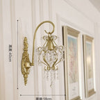 Decorative wall sconce with crystal details on a wall with framed pictures.