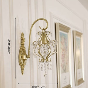 Decorative wall sconce with crystal details on a wall with framed pictures.