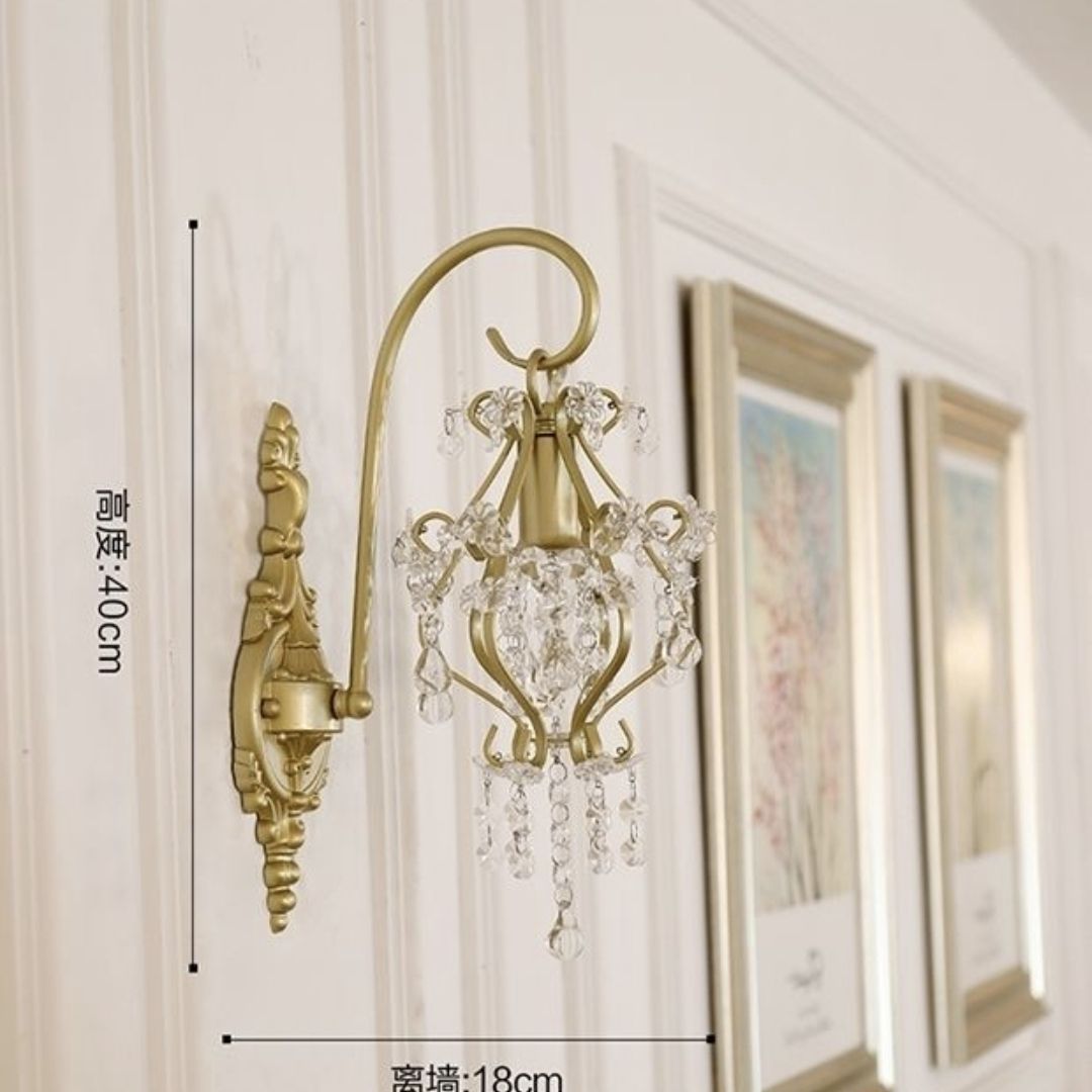 Decorative wall sconce with crystal details on a wall with framed pictures.